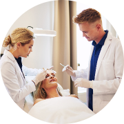 Clinical setting with two professionals performing a cosmetic brow treatment on a patient lying on a treatment bed; bright, sterile ambiance with a neutral color palette highlights professionalism and precision in aesthetic care.