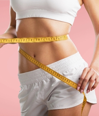 Close-up of a woman measuring her waist with a yellow tape measure, dressed in white sports attire against a soft pink background, emphasizing health, fitness, and self-improvement